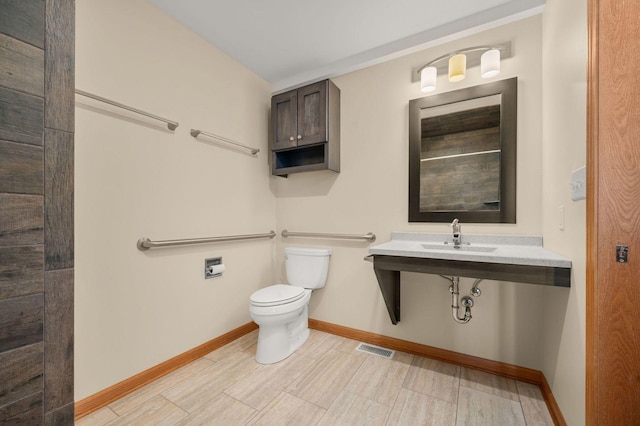 bathroom featuring visible vents, a sink, toilet, and baseboards