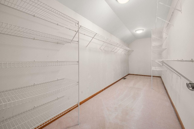 spacious closet with lofted ceiling and light colored carpet