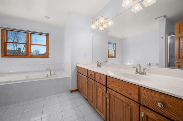 bathroom with double vanity, a garden tub, visible vents, and a sink