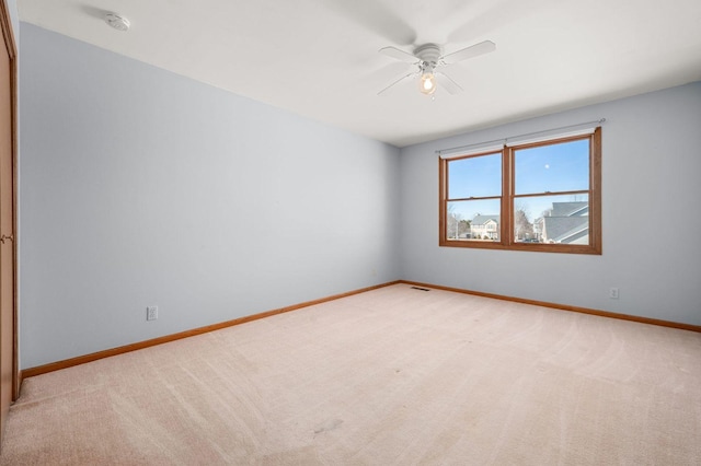 empty room with a ceiling fan, light carpet, visible vents, and baseboards