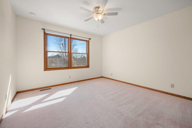 empty room with baseboards, visible vents, a ceiling fan, and light colored carpet