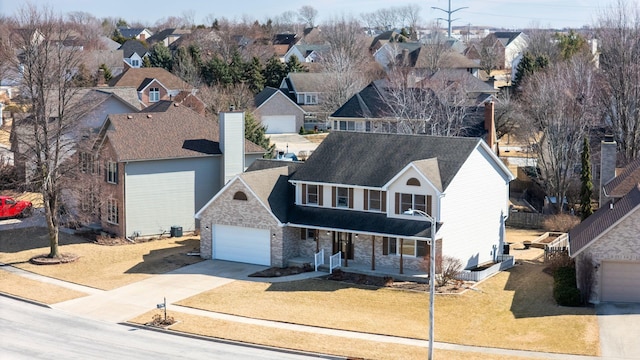 traditional-style house featuring an attached garage, a residential view, a front lawn, and concrete driveway