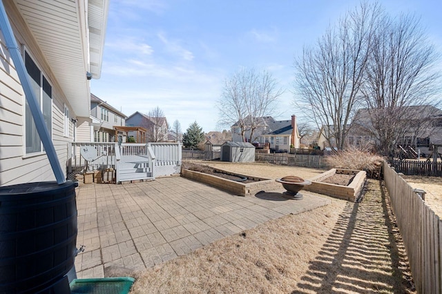 view of patio with an outbuilding, a fenced backyard, a vegetable garden, and a shed