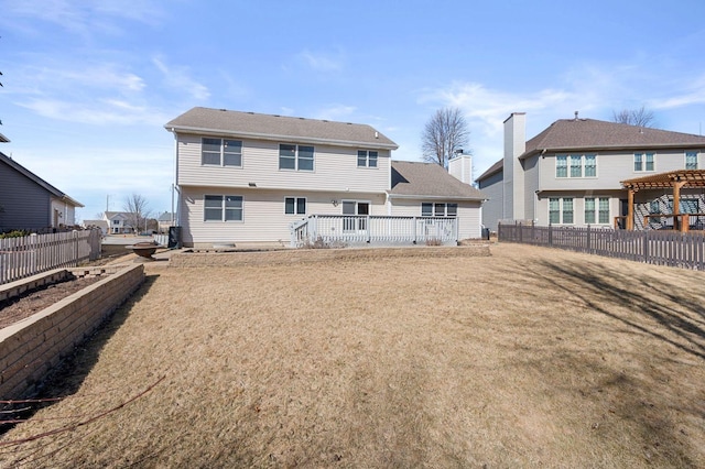 rear view of property featuring a yard, a deck, and fence