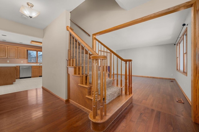 stairway featuring wood-type flooring, visible vents, and baseboards