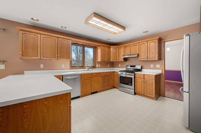 kitchen featuring light floors, stainless steel appliances, light countertops, under cabinet range hood, and a sink