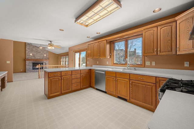 kitchen featuring a peninsula, a fireplace, vaulted ceiling, light countertops, and stainless steel dishwasher