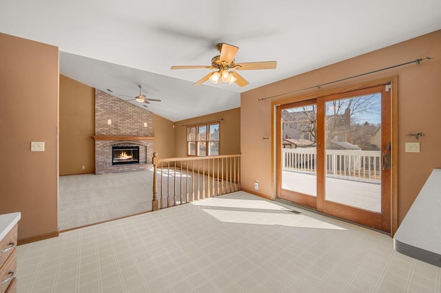 unfurnished living room featuring a wealth of natural light, a brick fireplace, light carpet, and lofted ceiling