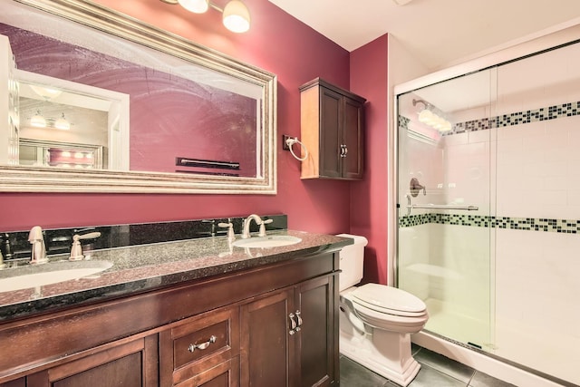 bathroom featuring tile patterned floors, toilet, a shower with shower door, and vanity