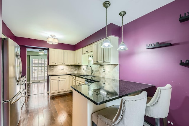 kitchen featuring pendant lighting, sink, a breakfast bar area, stainless steel refrigerator, and kitchen peninsula