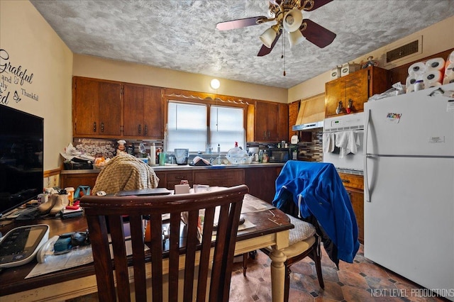 kitchen with ceiling fan, white appliances, and a textured ceiling