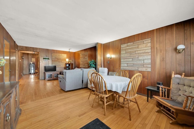 dining space with wooden walls and light wood-type flooring