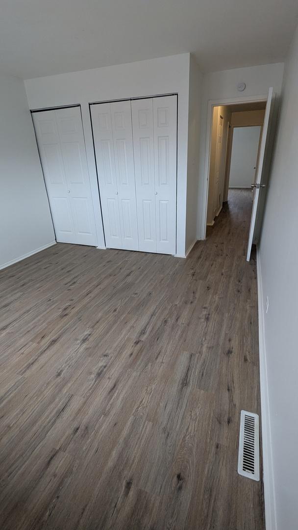 unfurnished bedroom featuring wood-type flooring and multiple closets