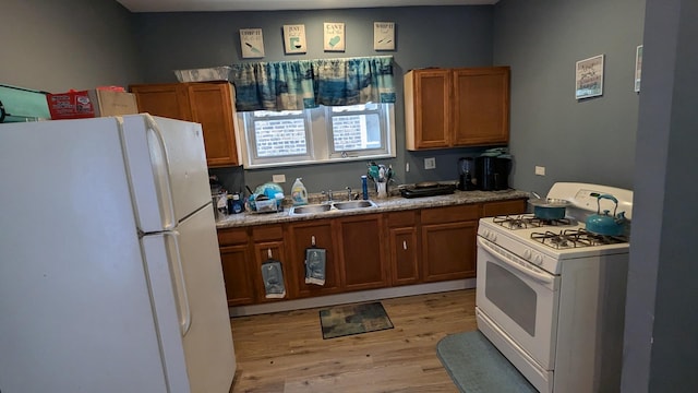 kitchen featuring white appliances, sink, and light wood-type flooring