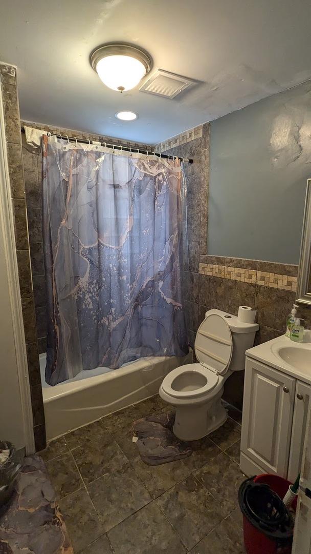 full bathroom featuring tile walls, vanity, shower / bath combination with curtain, and toilet