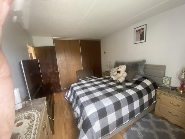 bedroom with dark hardwood / wood-style floors and a closet