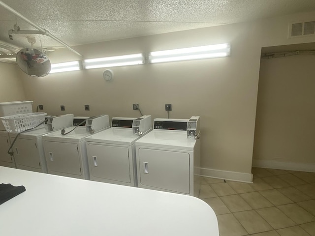 clothes washing area featuring a textured ceiling, washer and dryer, and light tile patterned floors