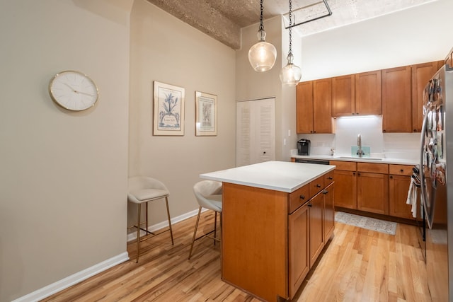 kitchen featuring pendant lighting, a center island, sink, and light wood-type flooring