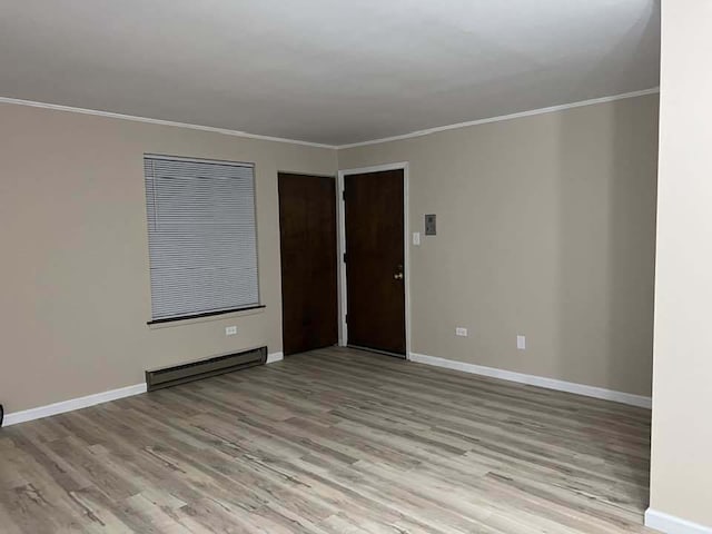 unfurnished room featuring light wood-type flooring, a baseboard radiator, baseboards, and crown molding