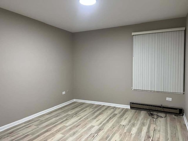 empty room featuring baseboards, light wood finished floors, and baseboard heating