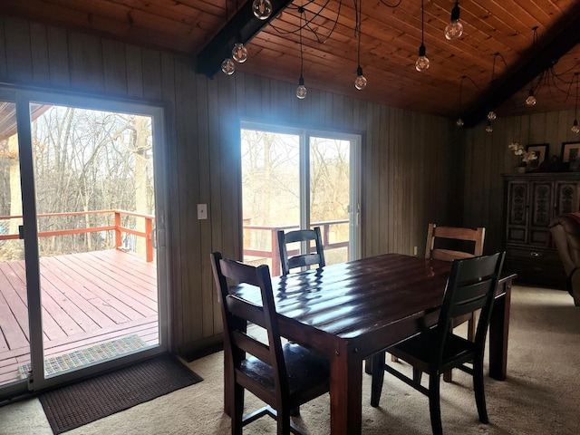 carpeted dining area with lofted ceiling with beams, wooden walls, and wood ceiling