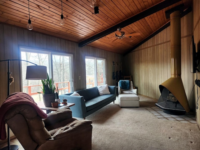 carpeted living room with vaulted ceiling with beams, wooden walls, wooden ceiling, and a wood stove