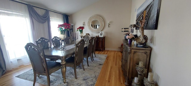 dining area with light hardwood / wood-style floors and vaulted ceiling