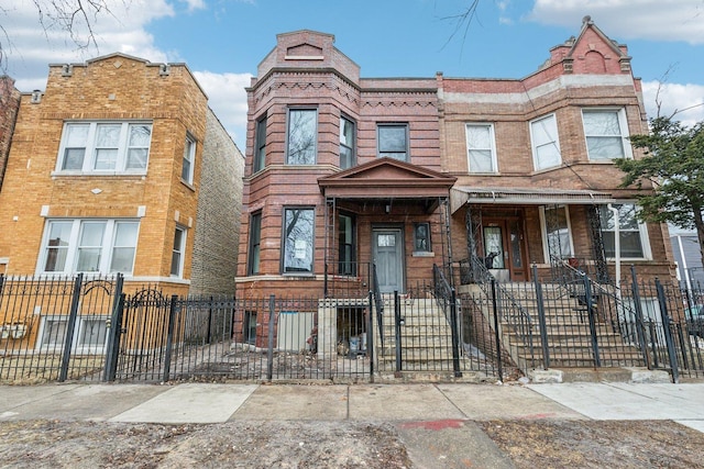 multi unit property featuring a fenced front yard and brick siding