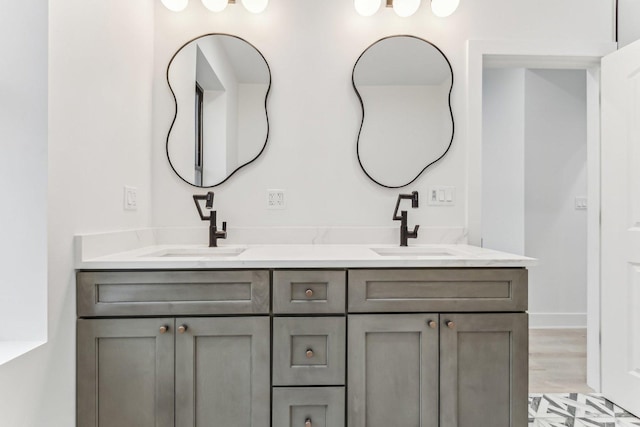 full bathroom with double vanity, baseboards, a sink, and wood finished floors