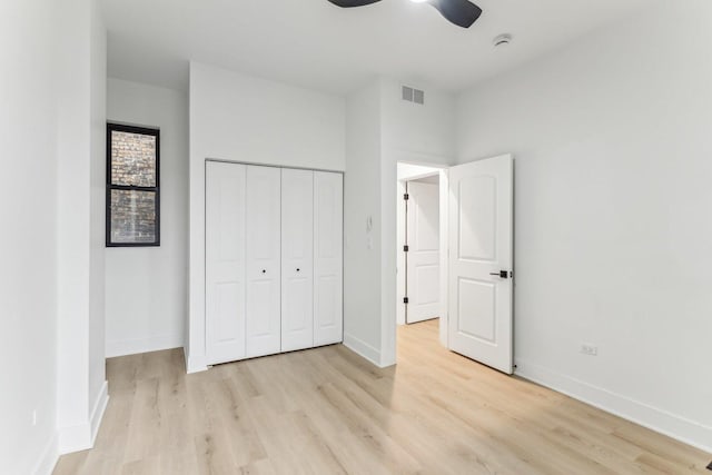 unfurnished bedroom featuring light wood-style flooring, a closet, visible vents, and baseboards