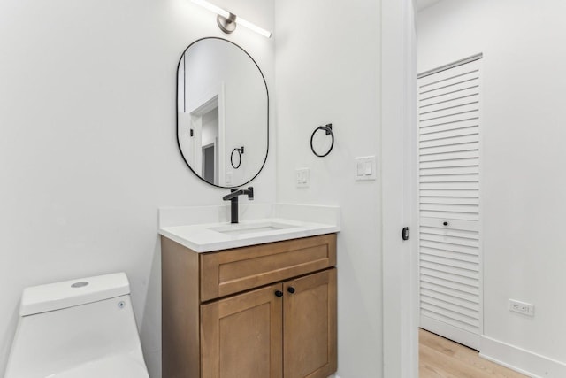 bathroom with baseboards, vanity, toilet, and wood finished floors