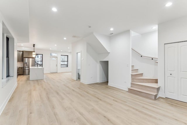 unfurnished living room featuring recessed lighting, light wood-style flooring, baseboards, and stairs