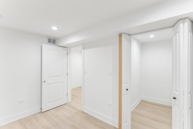 finished below grade area with light wood-style flooring, visible vents, baseboards, and recessed lighting