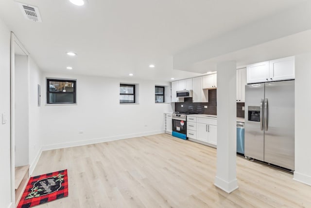 kitchen with stainless steel appliances, visible vents, white cabinetry, light wood finished floors, and tasteful backsplash