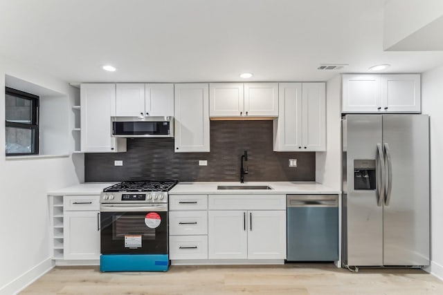 kitchen featuring open shelves, visible vents, appliances with stainless steel finishes, white cabinets, and a sink