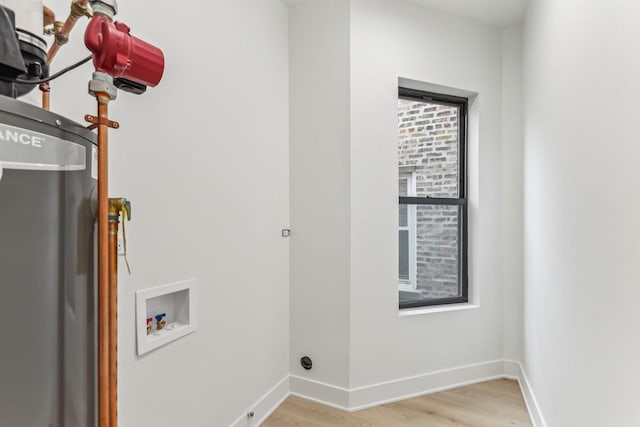 washroom with water heater, washer hookup, baseboards, and light wood-style floors