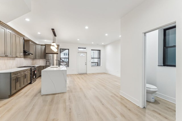 kitchen with an island with sink, decorative backsplash, stainless steel appliances, and light countertops