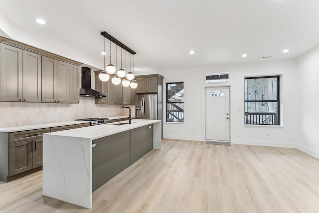 kitchen featuring plenty of natural light, wall chimney exhaust hood, stainless steel refrigerator with ice dispenser, and a sink