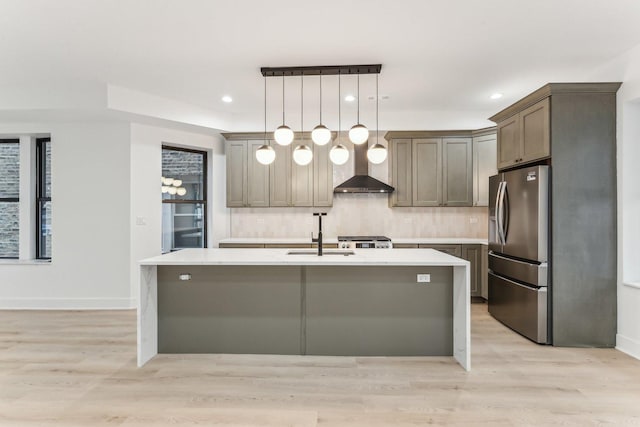 kitchen with light countertops, a sink, stainless steel refrigerator with ice dispenser, and an island with sink