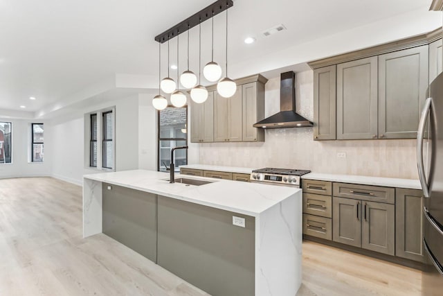 kitchen with light stone countertops, wall chimney range hood, light wood finished floors, and a sink