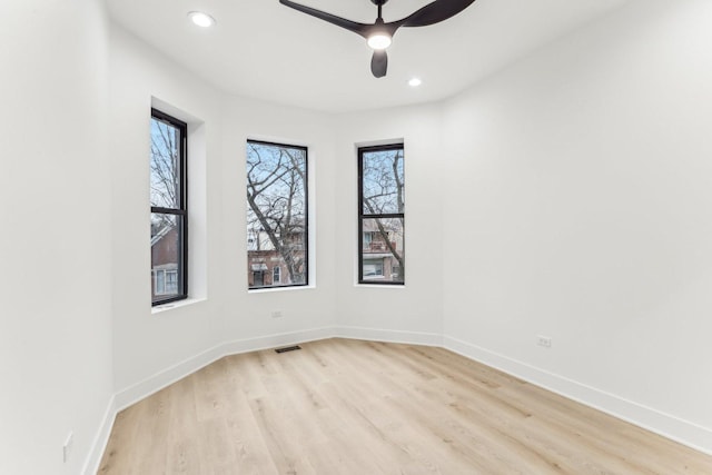 empty room featuring light wood finished floors, visible vents, baseboards, and a ceiling fan