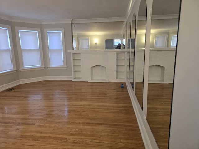 unfurnished living room with hardwood / wood-style floors, a brick fireplace, and ornamental molding