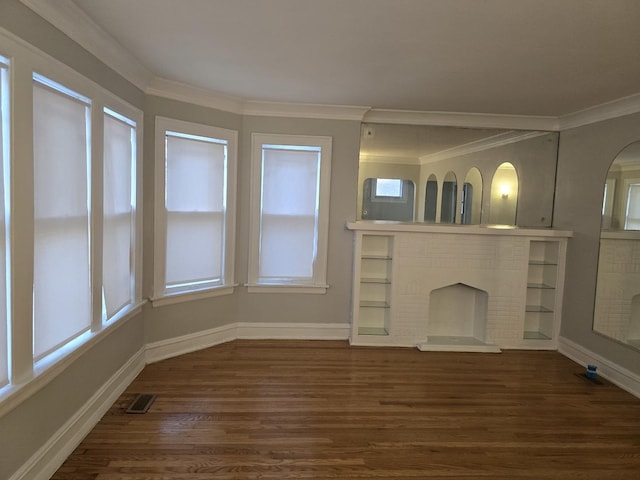 unfurnished living room with wood finished floors, crown molding, healthy amount of natural light, and a brick fireplace