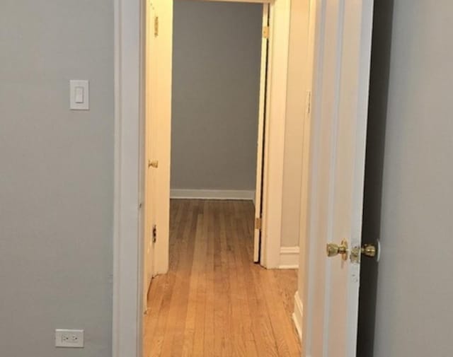 hall with light wood-style floors and baseboards