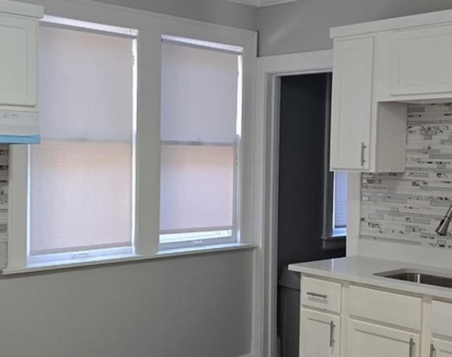 kitchen featuring decorative backsplash, white cabinetry, and light countertops