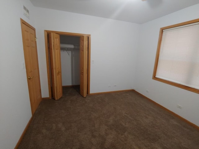 unfurnished bedroom featuring dark carpet and a closet