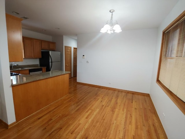 kitchen featuring pendant lighting, refrigerator, stone countertops, kitchen peninsula, and light wood-type flooring