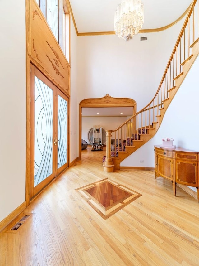 foyer with ornamental molding, stairway, wood finished floors, and visible vents