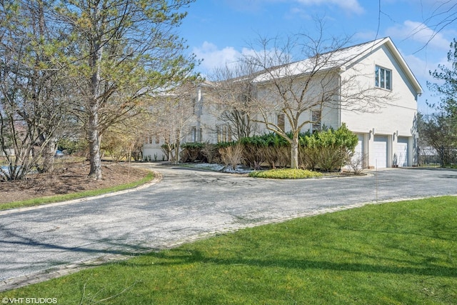 view of front of house featuring aphalt driveway, a front lawn, and a garage