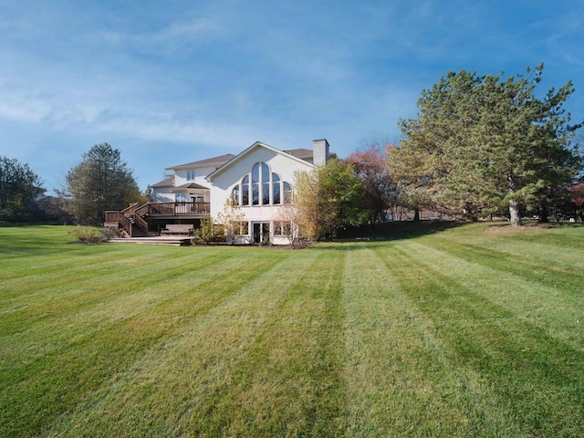 rear view of house with a chimney, a yard, and a deck